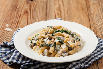 Fototapeta na wymiar Penne pasta with spinach and mushrooms. Sprinkled with cheese.