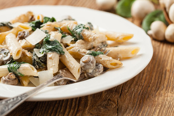 Penne pasta with spinach and mushrooms. Sprinkled with cheese.