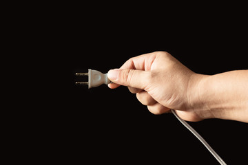 Hand holding a plug on a black background.