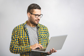 Confident business expert. Confident young handsome man in shirt holding laptop and smiling while...