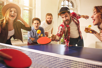 Group of happy young friends playing ping pong table tennis