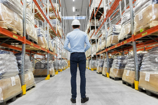 logistic business, shipment and people concept - businessman in helmet at warehouse