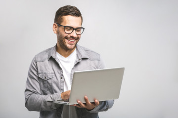 Confident business expert. Confident young handsome man in shirt holding laptop and smiling while...