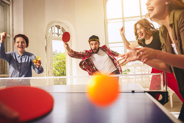 Group of happy young friends playing ping pong table tennis
