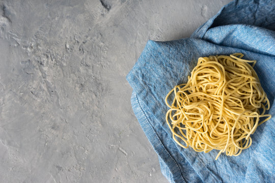 Rustic fresh pasta noodles linguine on blue towel with copy space