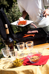 femme qui fait un barbecue avec des saucisses