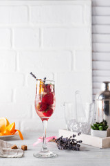 Refreshing cocktail with champagne and cranberry with ice, ginger and lavender on wooden background