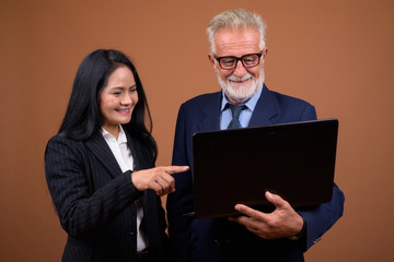 Mature multi-ethnic business couple against brown background