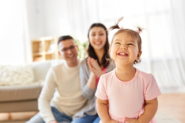 Fototapeta premium family and people concept - happy little daughter with mother and father at home