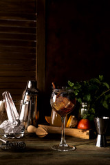 Red berry summer cocktail with brown sugar, cinnamon, blueberries and ice on dark wooden backgorund