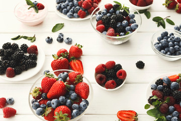 Mixed berries in glass bowls on white wooden table