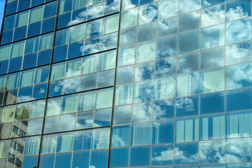 Fototapeta na wymiar Modern industrial building with glass. Reflection of blue sky with clouds in the windows.