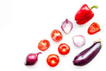Layout of contrast, colored vegetables. Eggplant, red onion, red pepper, tomato on white background top view copy space pattern
