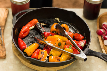 Seared peppers stuffed with cheese prepared in cast iron pan during camping trip