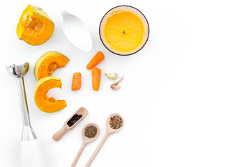 Cook orange cream soup with vegetables. Pumpkin, cream, spices, blender on white background top view copy space