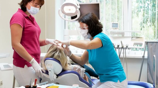4k panning video of dentist with assistant trating patient sitting in dental chair