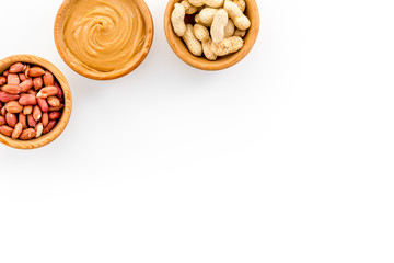 Peanut paste concept. Bowls with butter, nuts in shell, peeled nuts on white background top view copy space