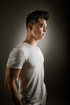 Side view of young man standing against gray background