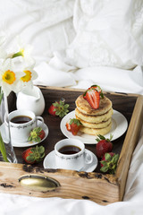 Breakfast in bed: cottage cheese pancakes, coffee and strawberries