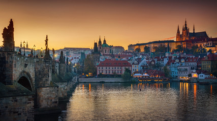 Fototapeta na wymiar Panoramic view of night time illuminations of Prague Castle, Charles Bridge and St Vitus Cathedral reflected in the Vltava river. Pragua, Czech Republic.
