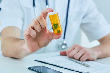 Male medicine doctor hand hold jar of pills and explain how to take pills to patient at worktable. Panacea and life save prescribing treatment legal drug store concept. - 204951393