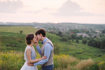 Romantic and happy caucasian couple in stylish clothes hugging on the background of beautiful nature. Love, relationships, romance, happiness concept. Man and woman walking outdoors together.