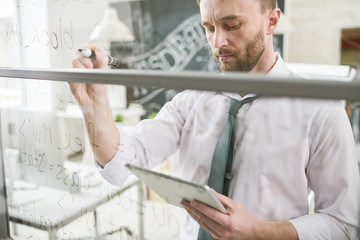 Waist up portrait of handsome businessman wearing shirt and tie brainstorming problem and writing...