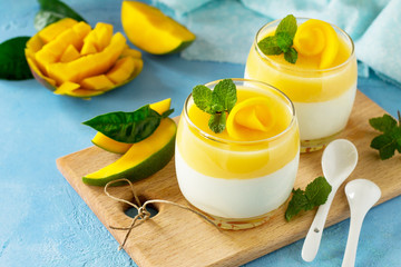 Italian dessert panna cotta decorated with fresh mango and mint on a blue a stone or slate...