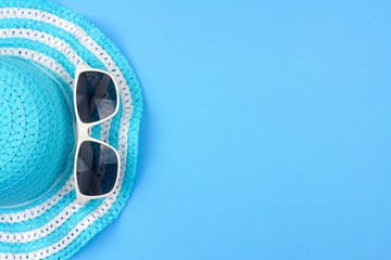 Summer hat with sunglasses. Top view, minimal concept over a blue background. Side border...