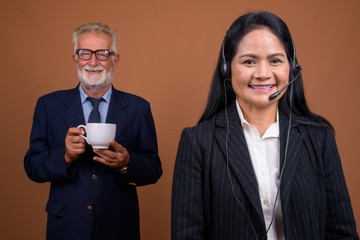 Mature multi-ethnic business couple against brown background