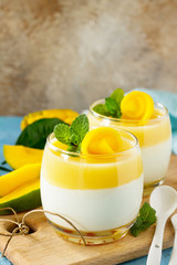 Mango panna cotta with fresh mango and topping with mango jelly on a stone or slate background....