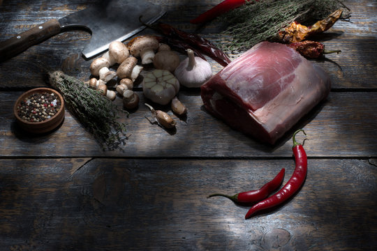 Raw beef steaks, ready for roasting, salt, pepper, mushroom, garlic, tym, ax for chopper of meat on wooden background. Top view