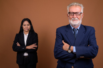 Mature multi-ethnic business couple against brown background