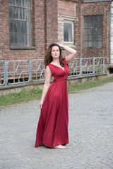 erotische junge Frau in langen roten Kleid auf altem Fabrikgelände