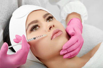 Sideview of cosmetological lips enlargment process. Medical injection for plump, soft, large lips....