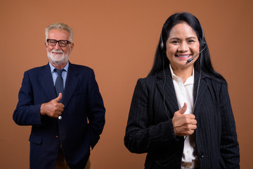 Mature multi-ethnic business couple against brown background