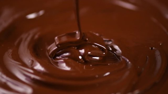 Chocolate. Pouring melted liquid premium dark chocolate closeup. Confectionery. Slow motion 4K UHD video 3840X2160