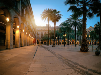 Fototapeta na wymiar Sun rises over illuminated Plaza Real in in Gothic quarter of Barcelona, Spain
