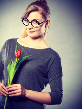 Seducive nerdy girl holding tulip.