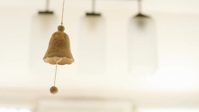 close up view of beautiful handmade ceramic bell moving in the air with amazing ornament bird in love picture on while background day light wedding theme Christmas decoration lovely nice pretty design