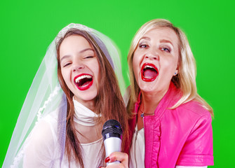 Young Singer bride and her sister with a microphone celebrating her forthcoming mariage. Studio shot. Bright colorful background.