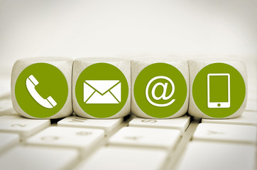 Website and Internet contact us page concept with green icons on cubes on a keyboard

