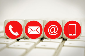 Website and Internet contact us page concept with red icons on cubes on a keyboard

