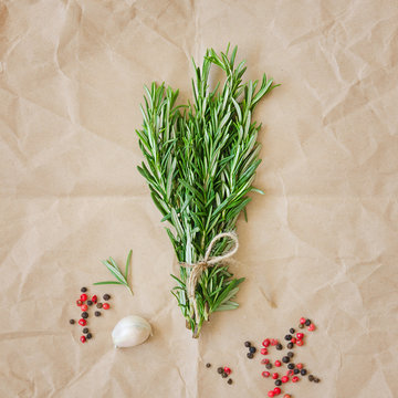 Bunch of rosemary with garlic and spices on wrapping paper