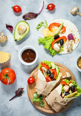 Healthy vegan lunch snack. Tortilla wraps with mushrooms, fresh vegetables and Ingredients on concrete background.