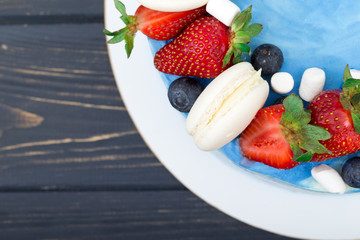 Sweet cake with strawberries on plate on grey wooden background