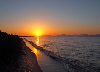 beautiful golden sunset reflected on the sea and wet beach sand in Kos Greece