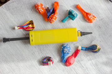 Yellow pump for blowing balloons with vivid balloons on a table.