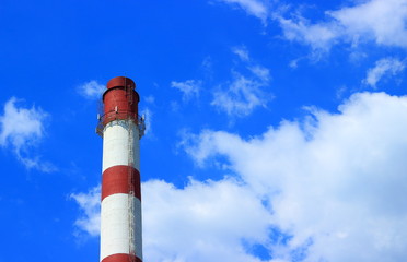 Industrial landscape with boiler pipe with red and white stripes against on a blue sky with clouds background with copy space.