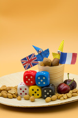 Vertical View of Peanuts, Five Colored Dices, Two Cherries and the France and Great Britain National Flags and Two Funny Faces